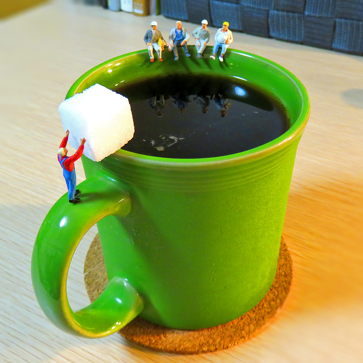 コーヒーに角砂糖を入れる作業員とコーヒーブレイクする現場作業員